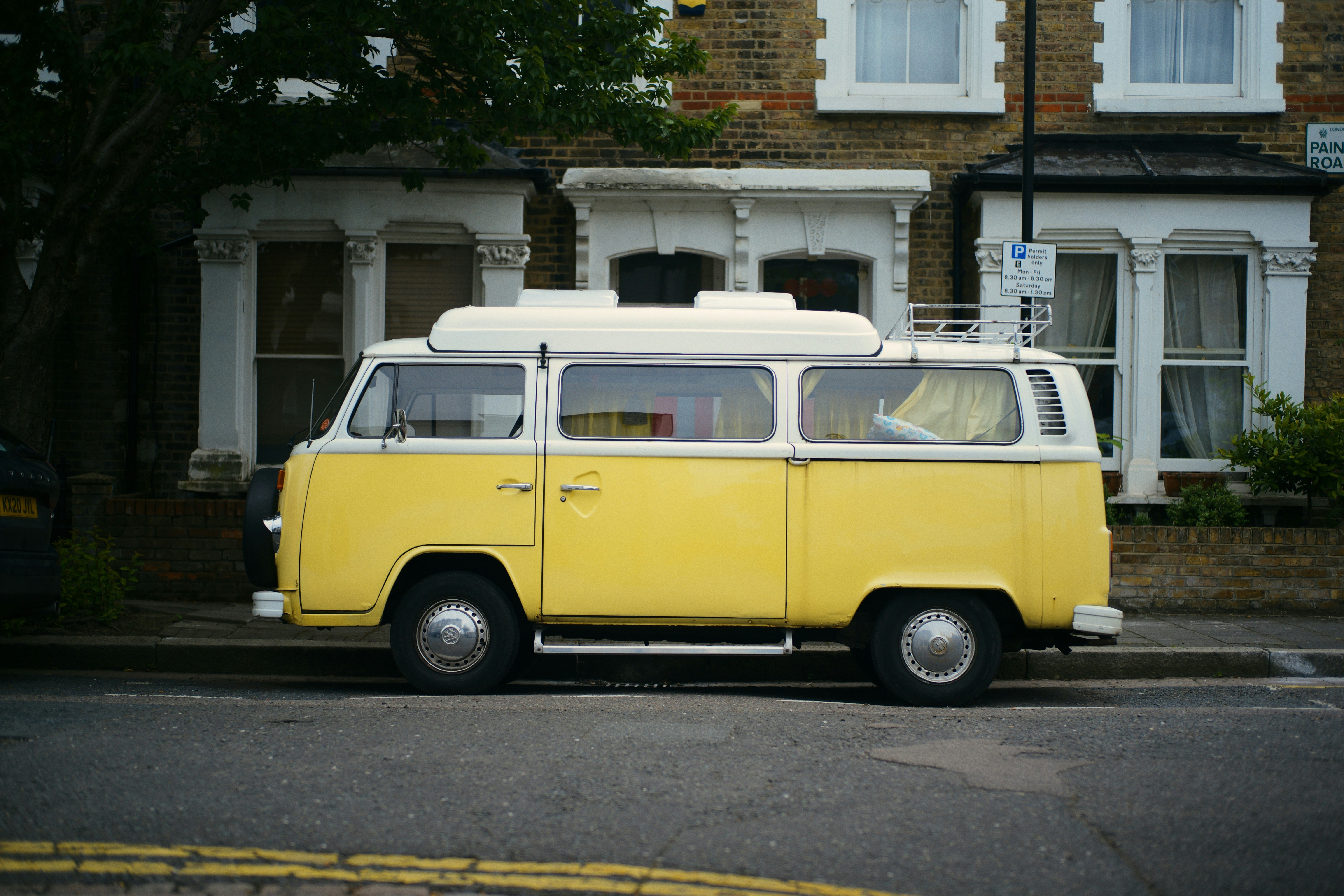 volkswagen t-2 amarillo y blanco estacionado en la carretera durante el día
