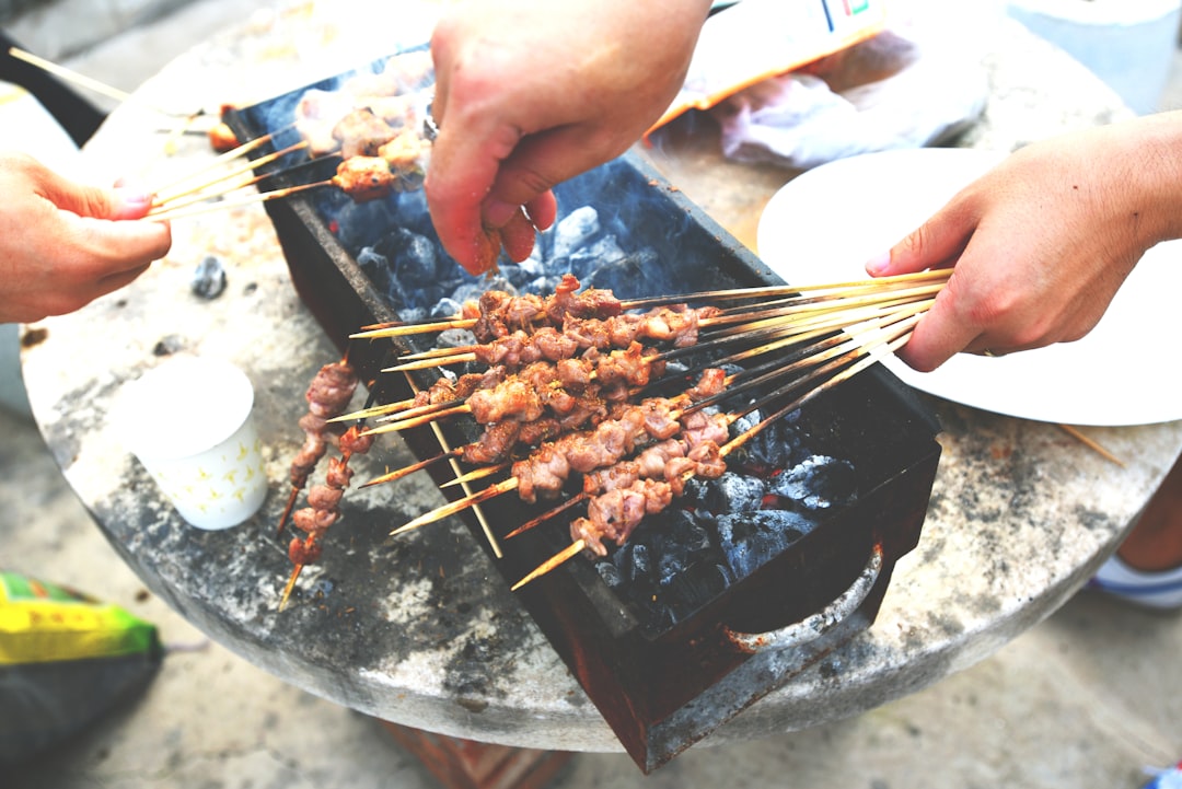 person holding fork and knife slicing meat on black and gray grill