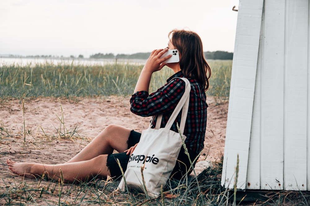 woman in black and white checkered long sleeve shirt sitting on brown grass field during daytime