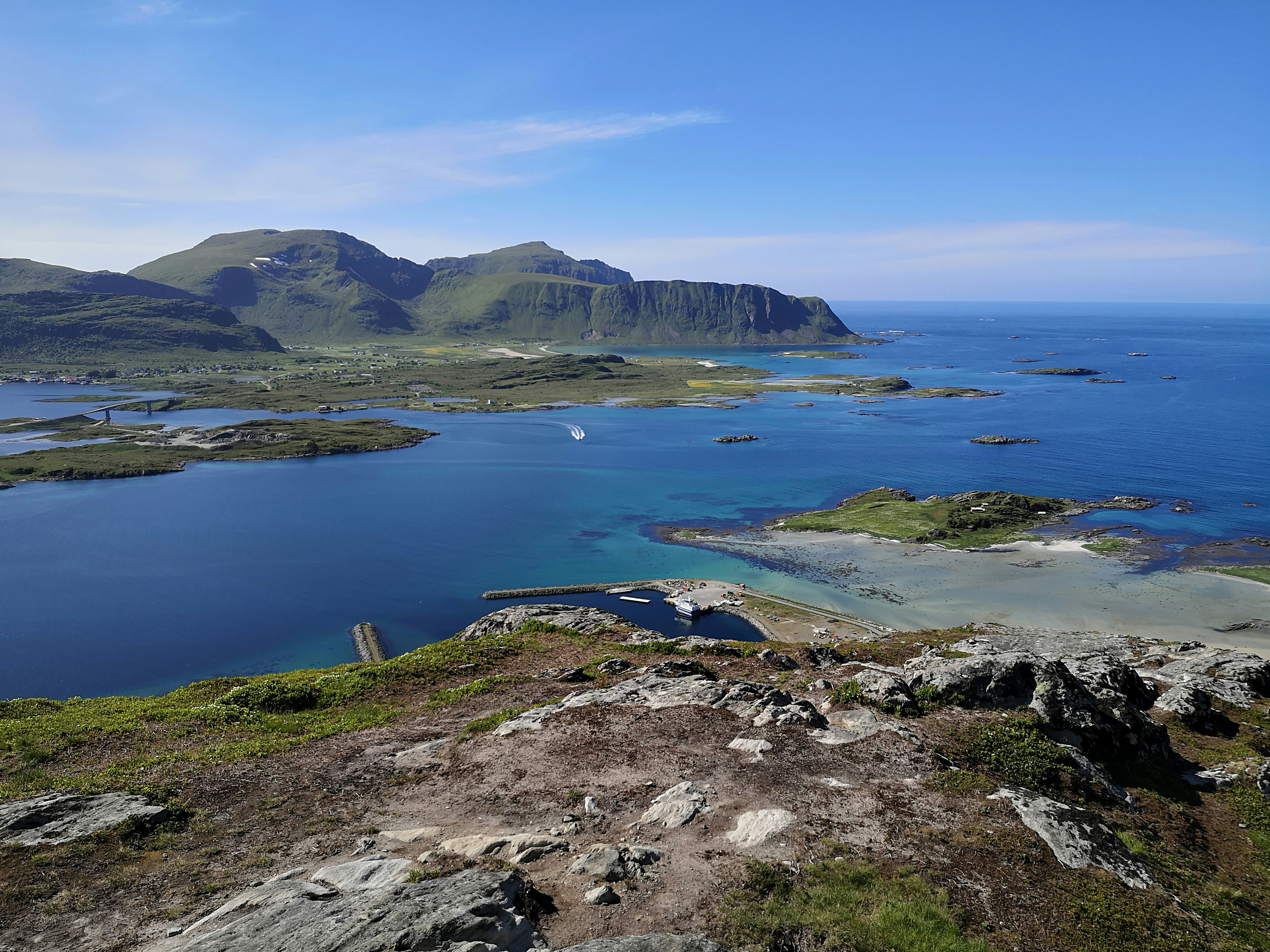 green and brown mountain beside blue sea under blue sky during daytime