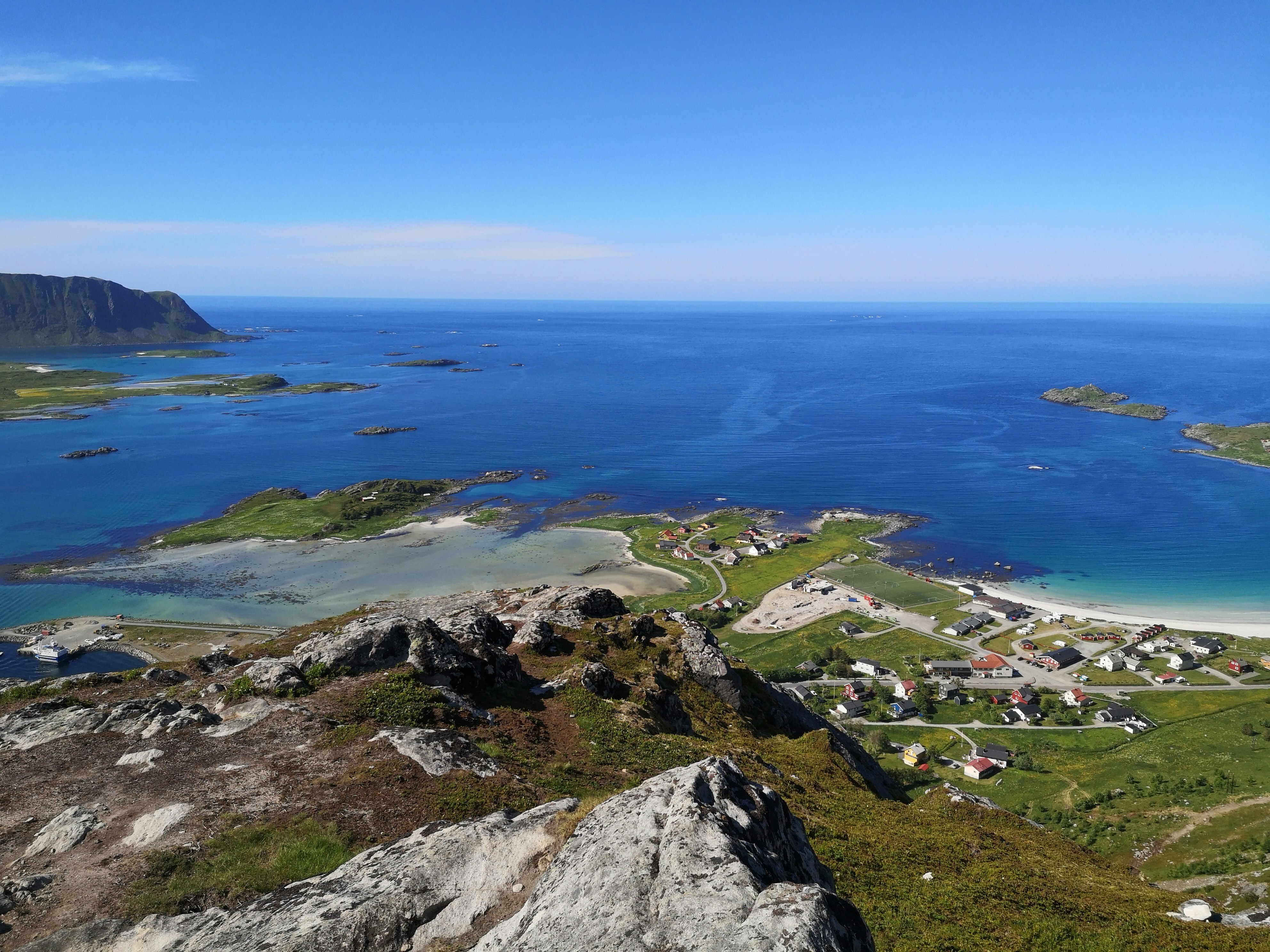 green grass covered mountain near body of water during daytime