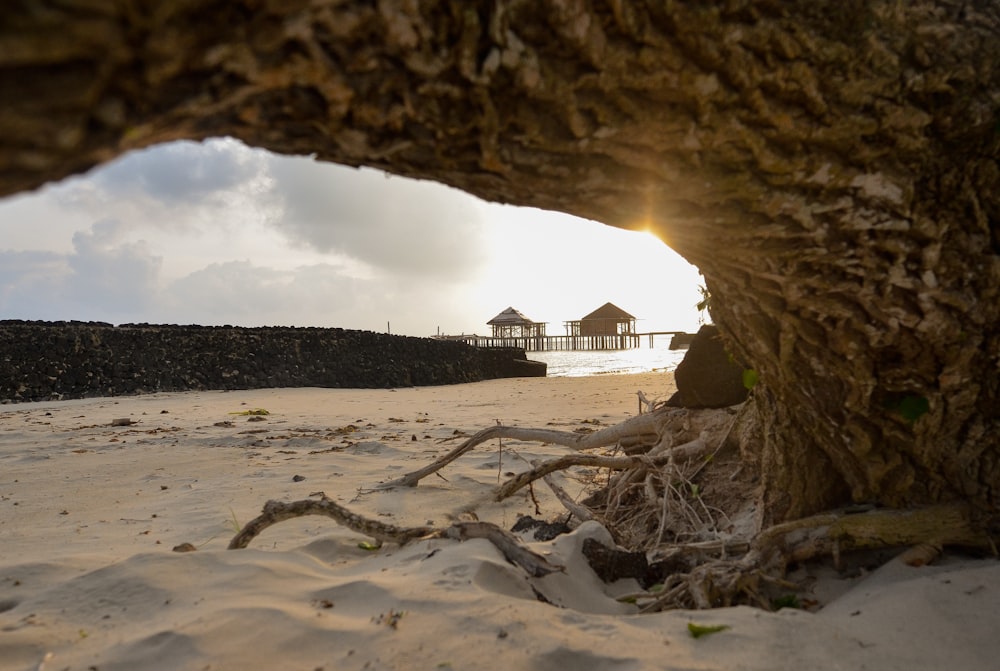 Braunes Holzhaus auf weißem Sand unter weißen Wolken tagsüber