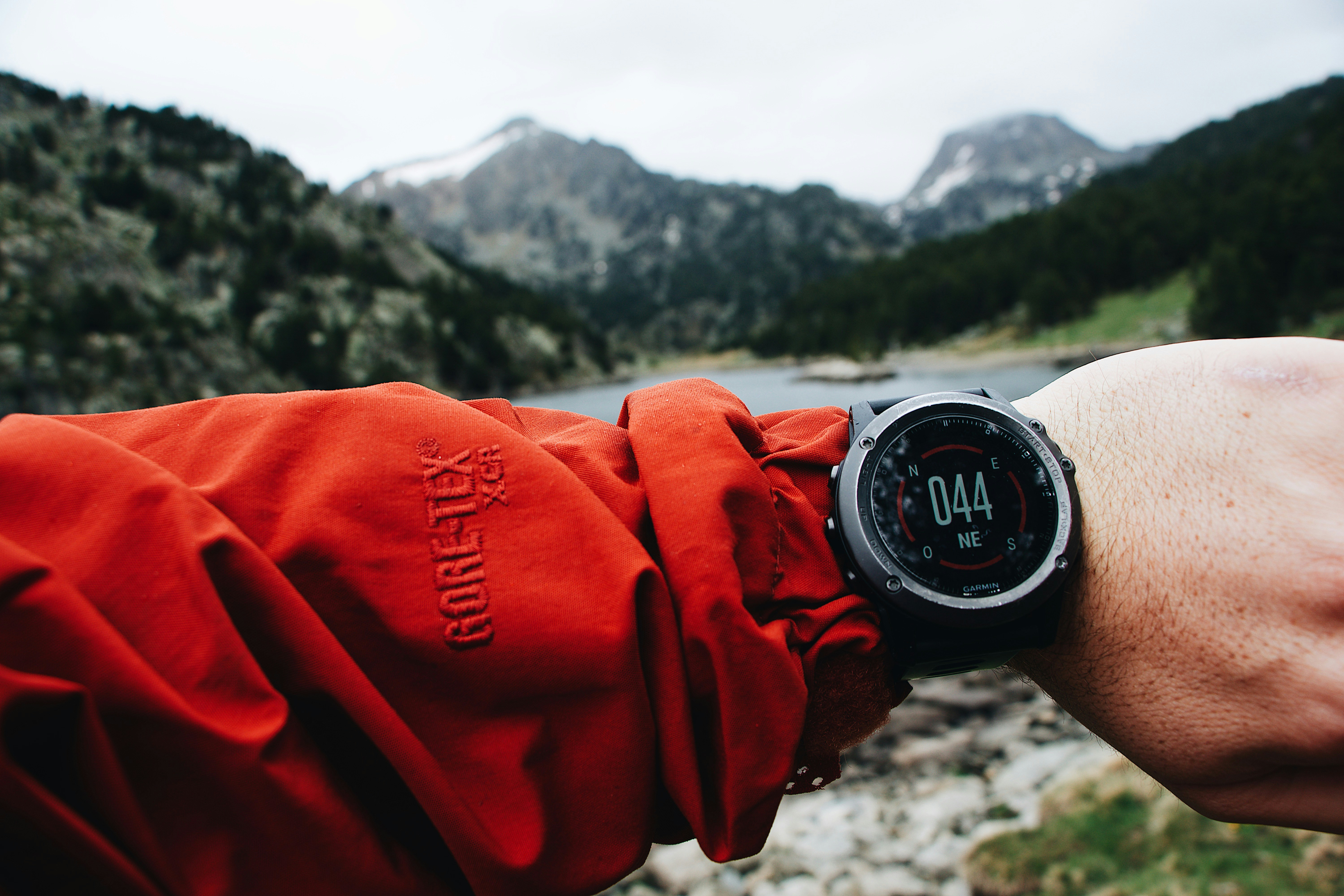 person in red jacket holding black and silver round digital watch
