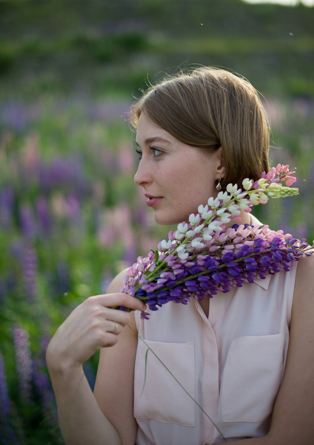 woman in white coat holding purple flower