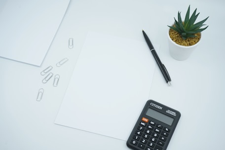 A minimalist office desk with tax documents and a calculator in green and blue tones.