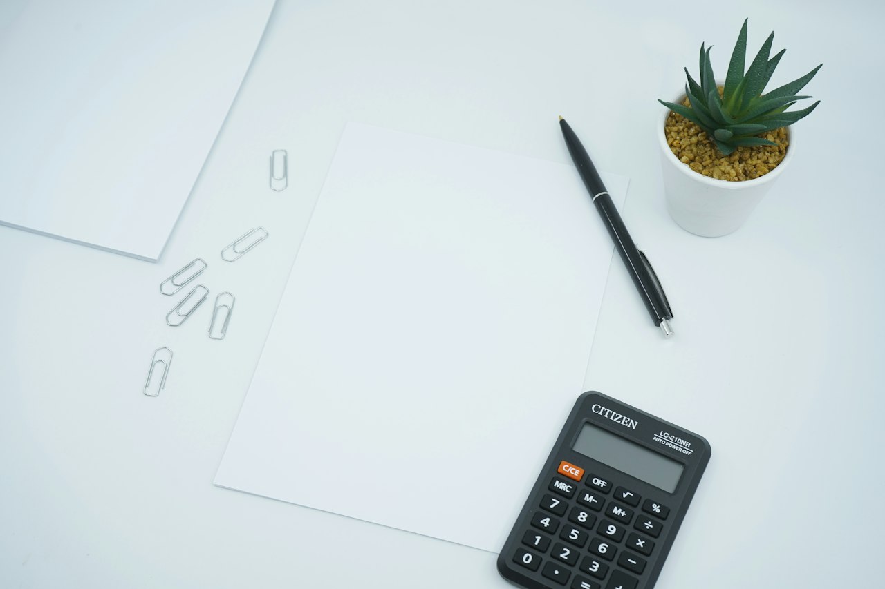 Calculatrice noire, stylo et papier blanc sur bureau
