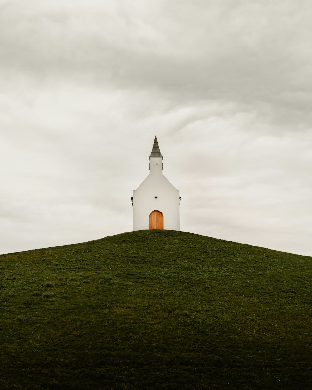 white concrete church on green grass field under gray cloudy sky