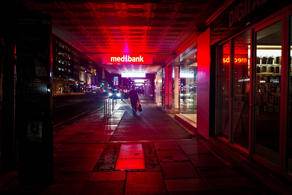 homem em jaqueta preta andando na calçada durante a noite