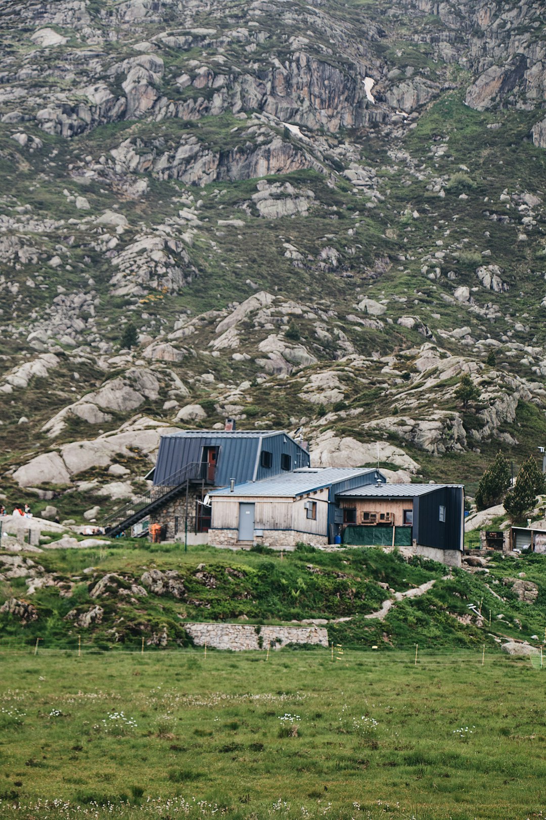 white and blue house on green grass field near gray rocky mountain during daytime