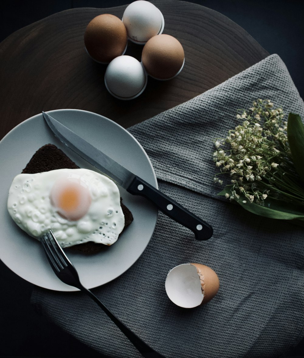 egg on white ceramic plate beside stainless steel fork and knife
