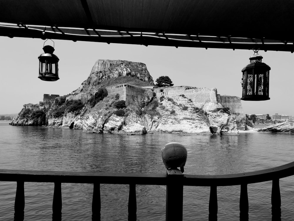 grayscale photo of rock formation near body of water