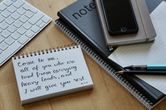 white notebook beside black pen on brown wooden table
