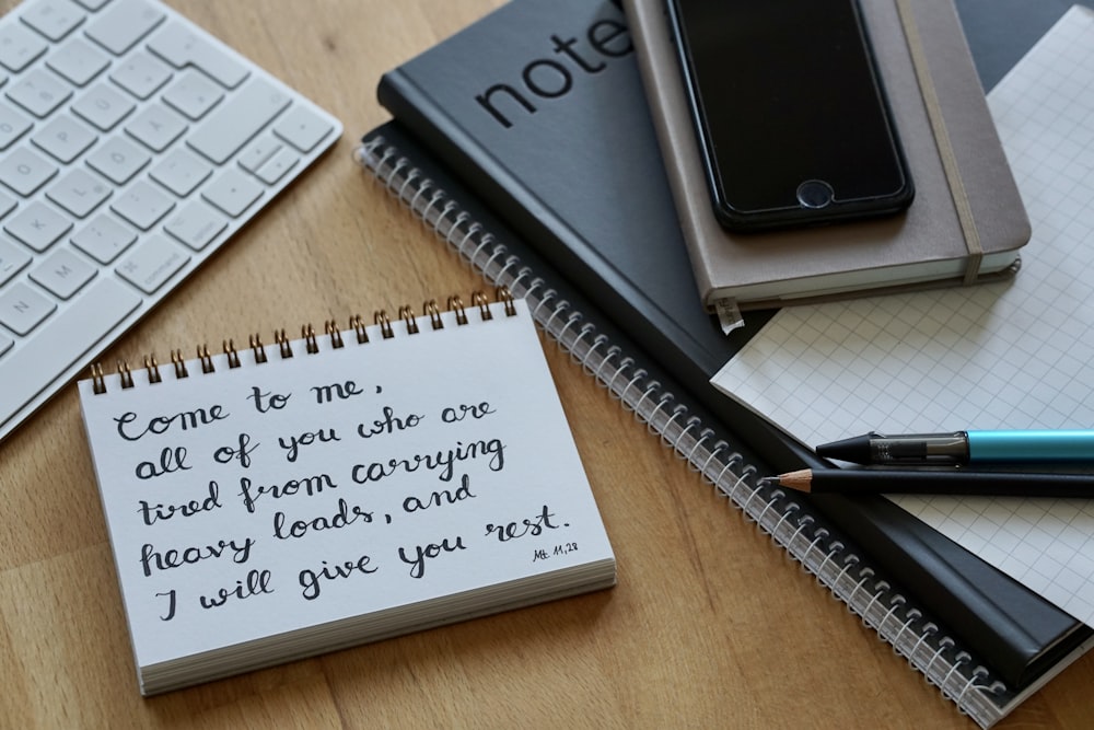 white notebook beside black pen on brown wooden table