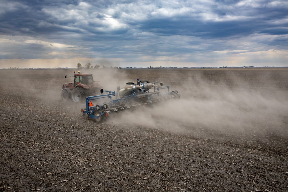 blue and red atv on brown soil under white clouds and blue sky during daytime