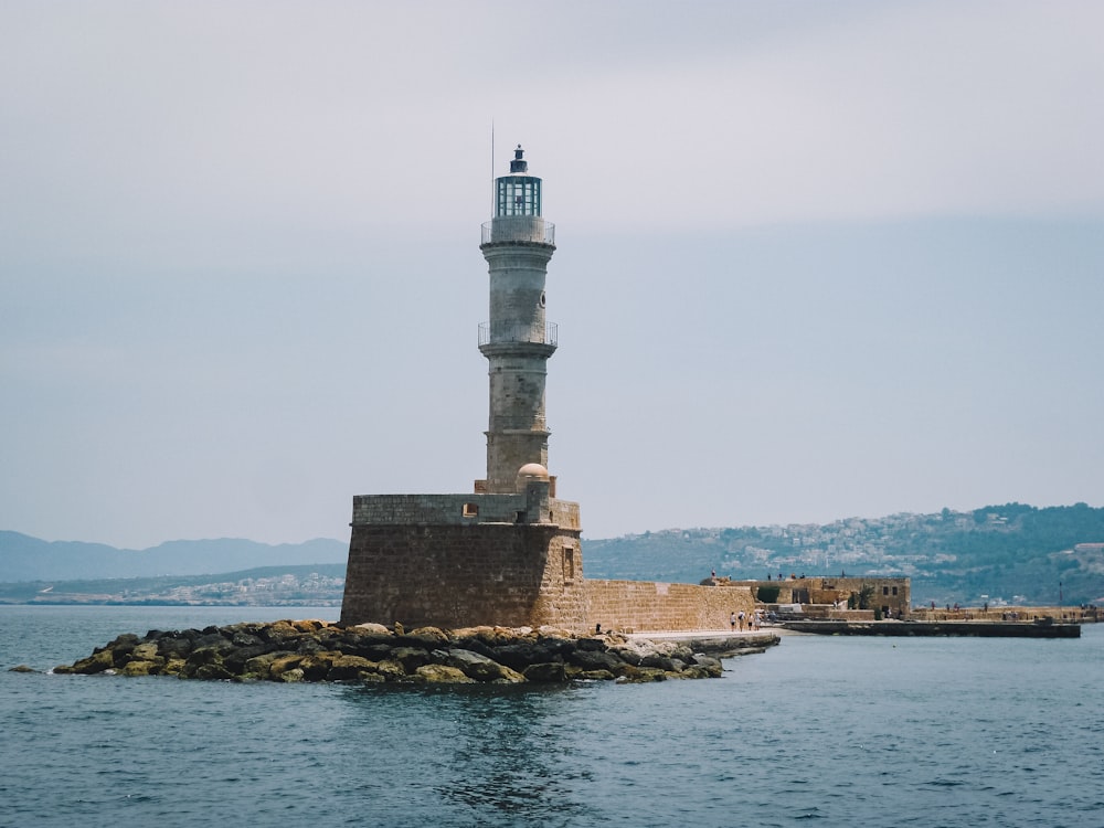 white and black lighthouse near body of water during daytime