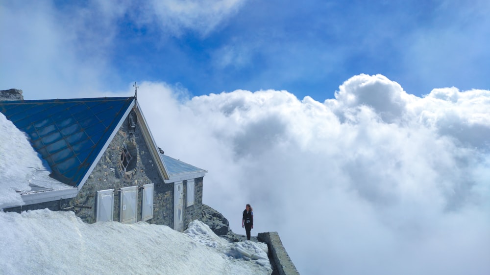 person in black jacket standing on gray concrete building under white clouds and blue sky during