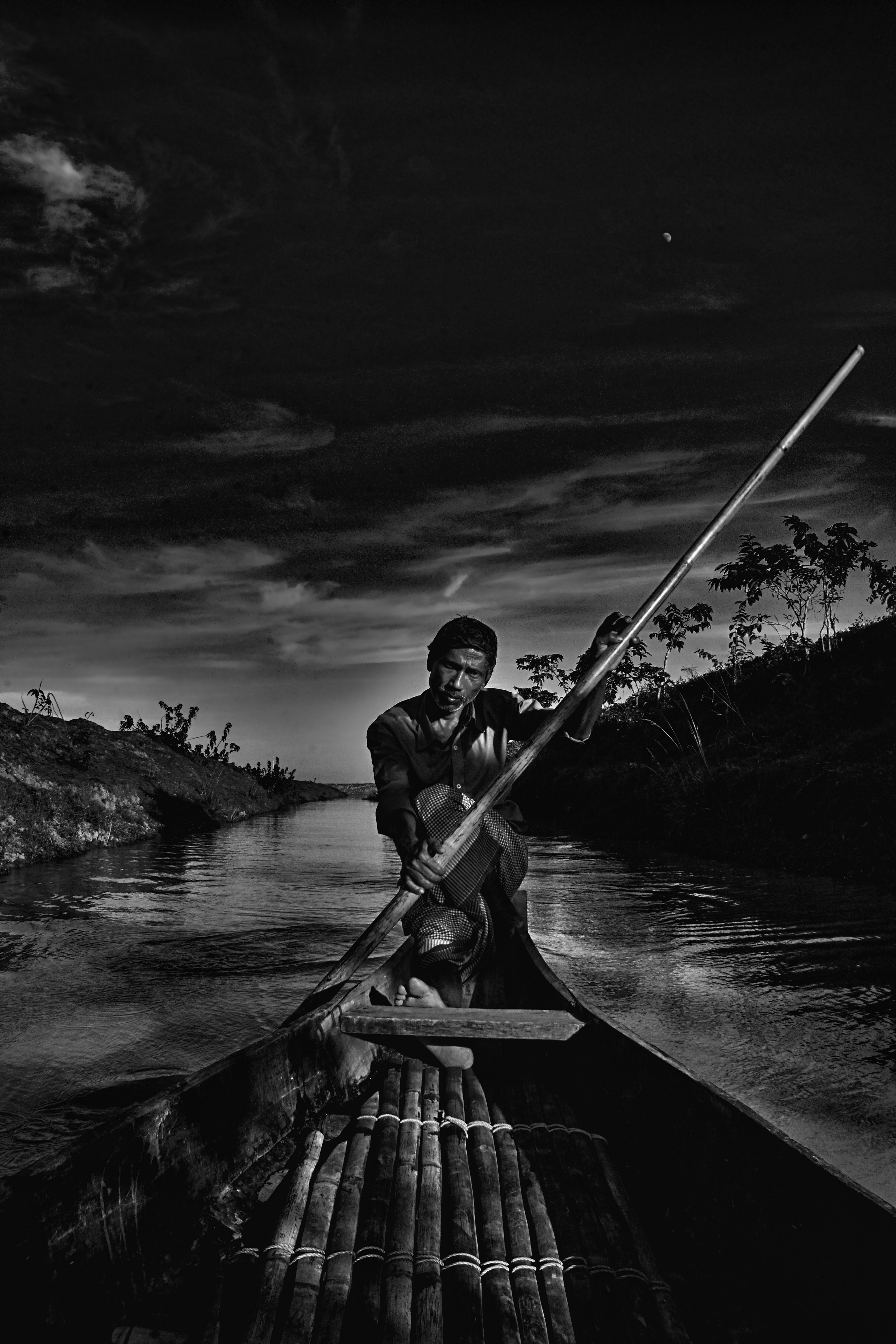grayscale photo of man riding canoe on river