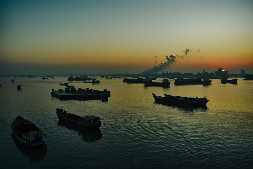 silhouette of boats on sea during sunset