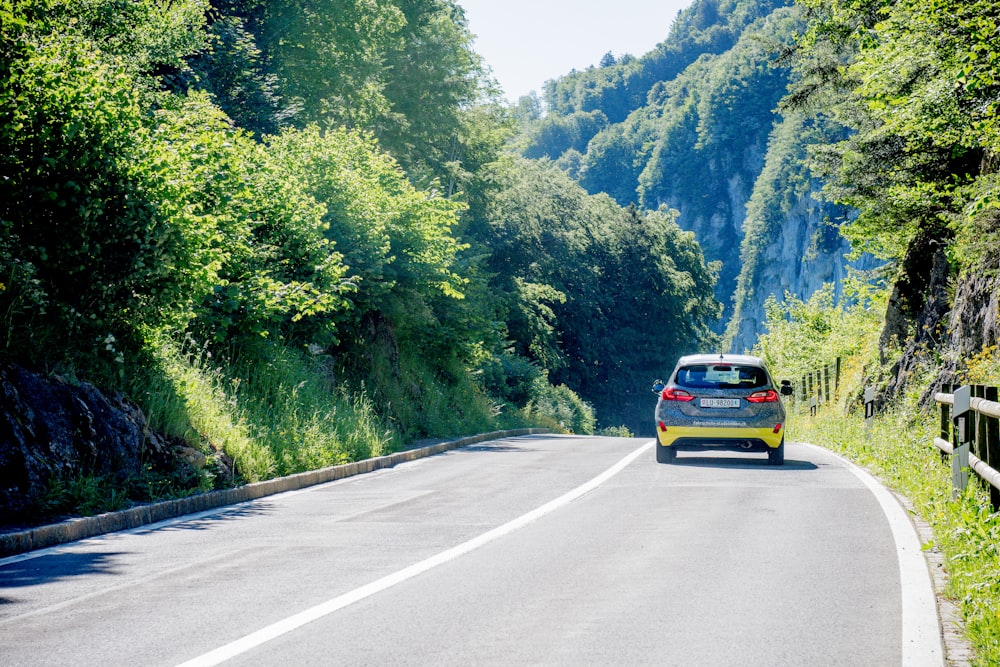 yellow car on road near green trees during daytime