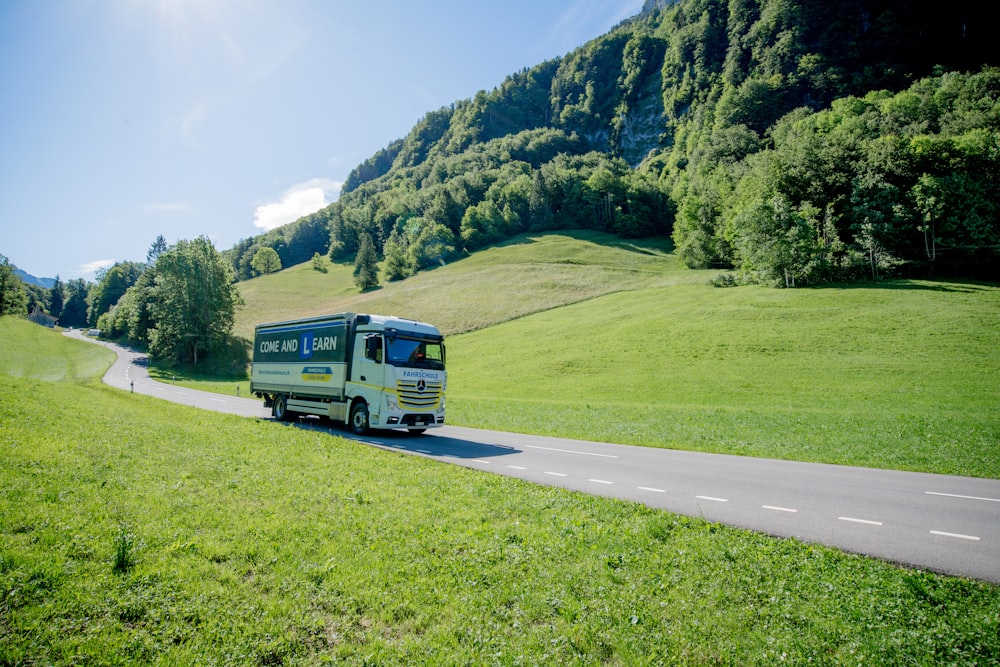 blue van on road near green grass field and green mountains during daytime