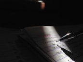 Close-up of handwritten notes and scripts illuminated by a desk lamp.