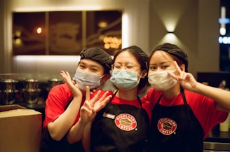 2 women in red and black polo shirt wearing mask