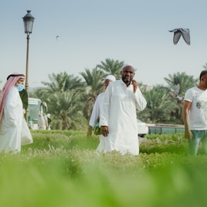 man in white thobe standing on green grass field during daytime