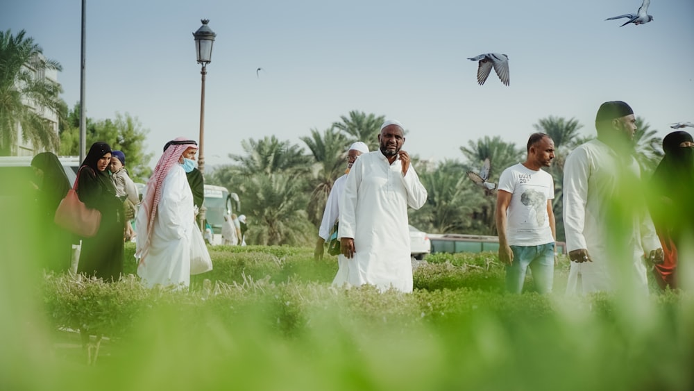 man in white thobe standing on green grass field during daytime