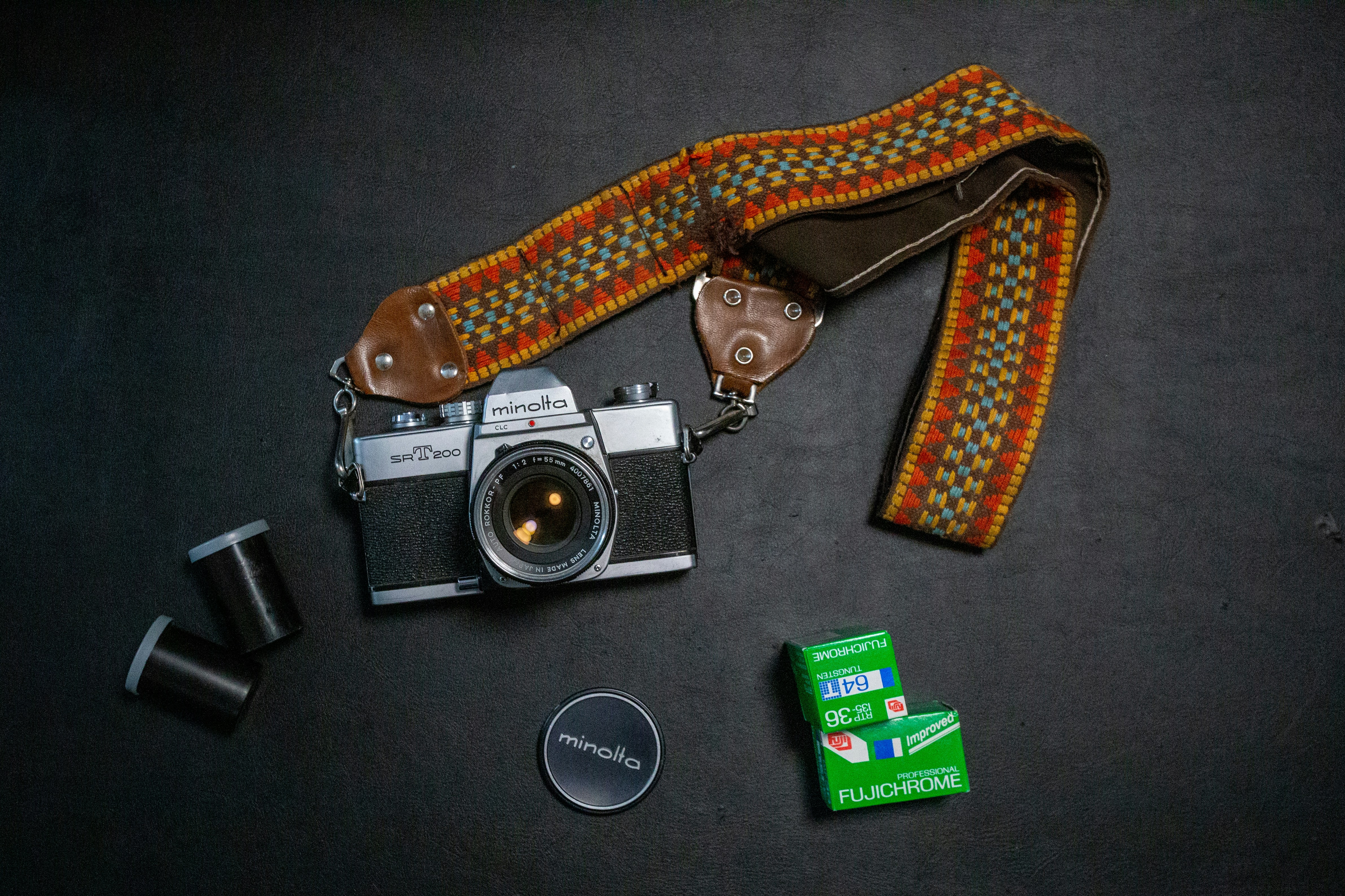 black and silver dslr camera beside brown and black strap
