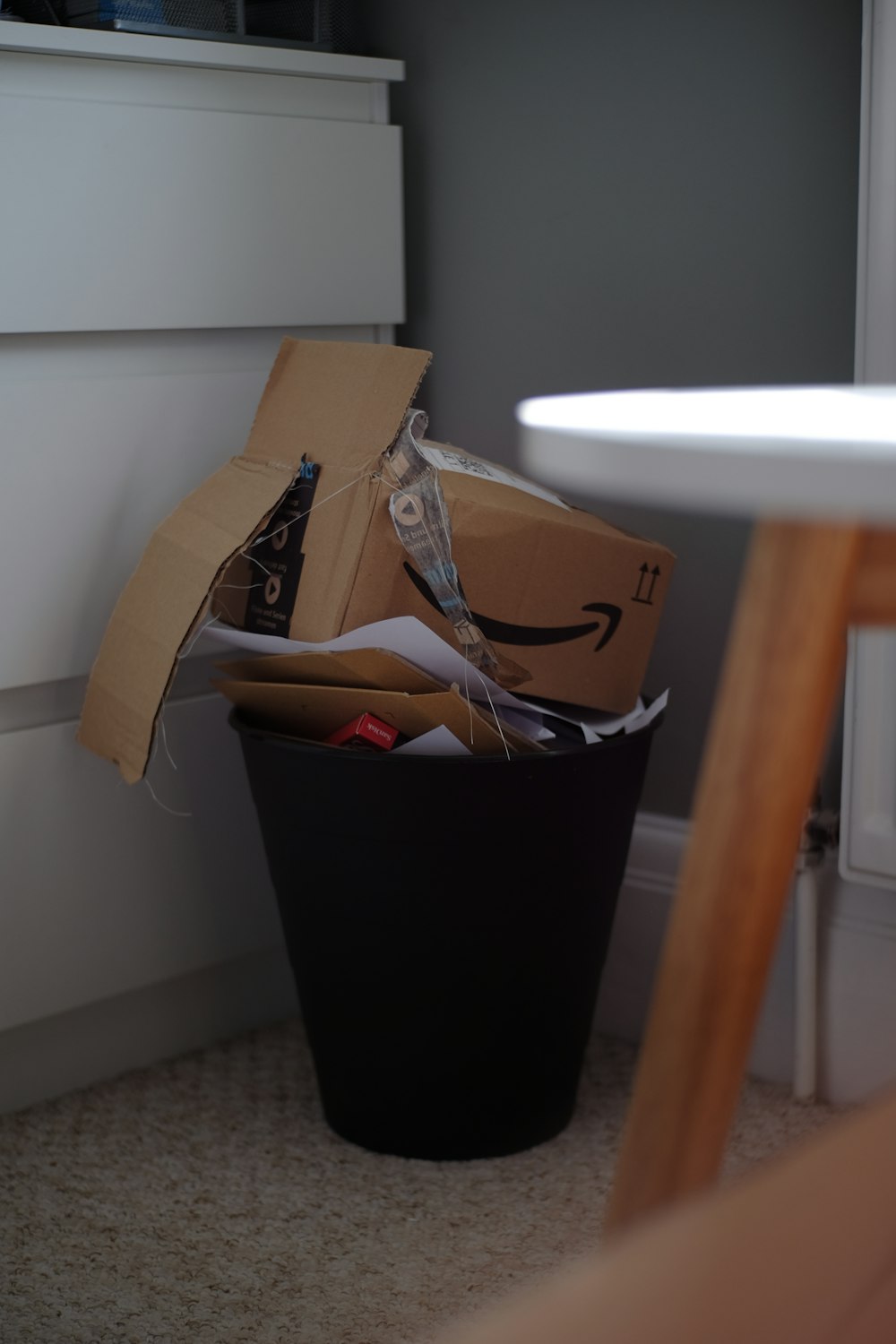 brown cardboard box on black plastic trash bin