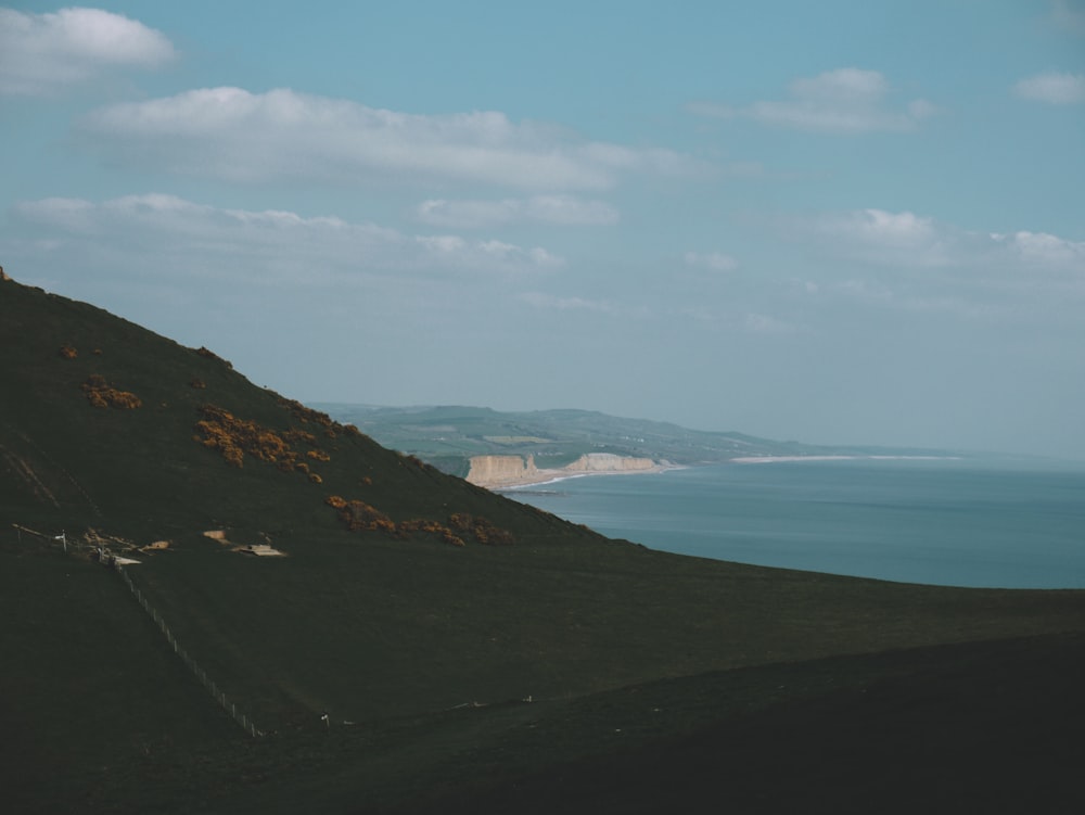 body of water near mountain under blue sky during daytime