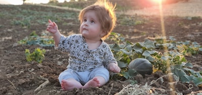Children playing barefoot in a sunlit garden surrounded by vegetable plants