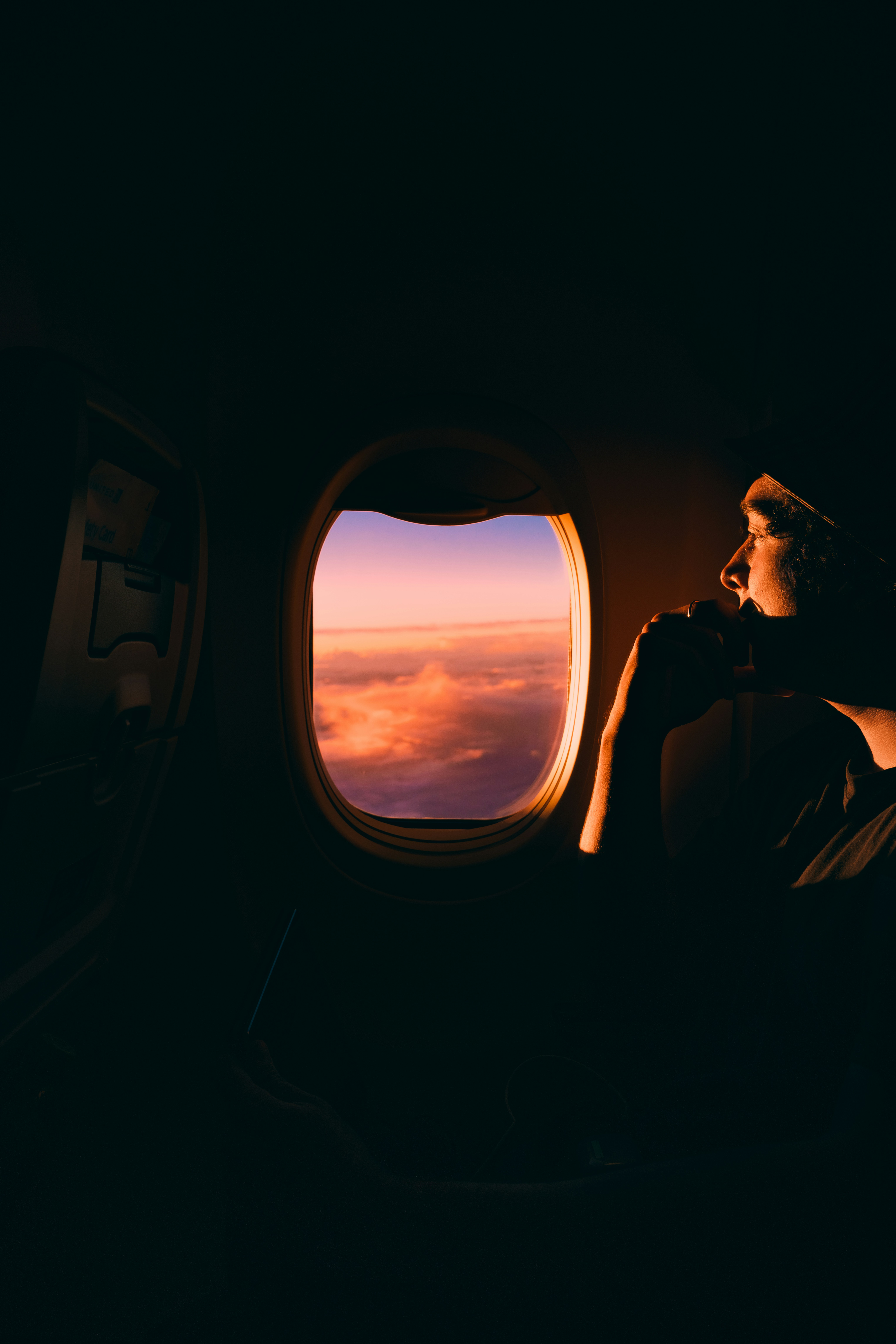 Young man looking at sunrise over an airplane window