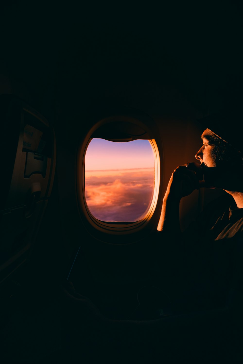 Hombre en chaqueta negra sentado en el asiento del coche mirando a la ventana durante la puesta del sol