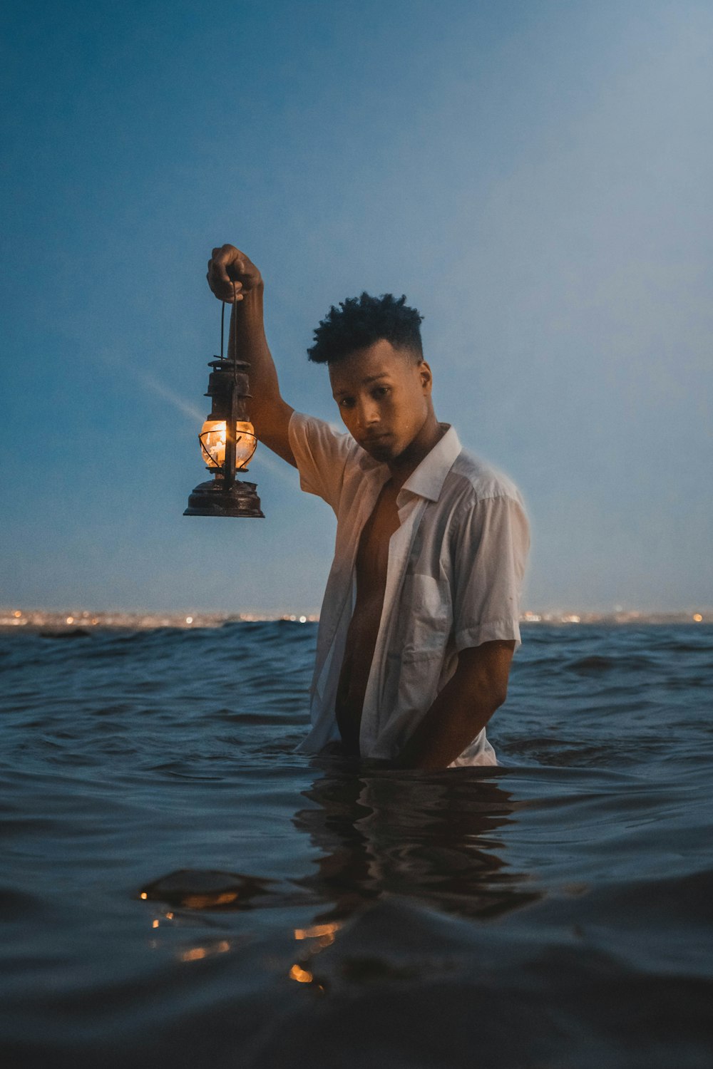 man in white shirt holding gold trophy on body of water during daytime