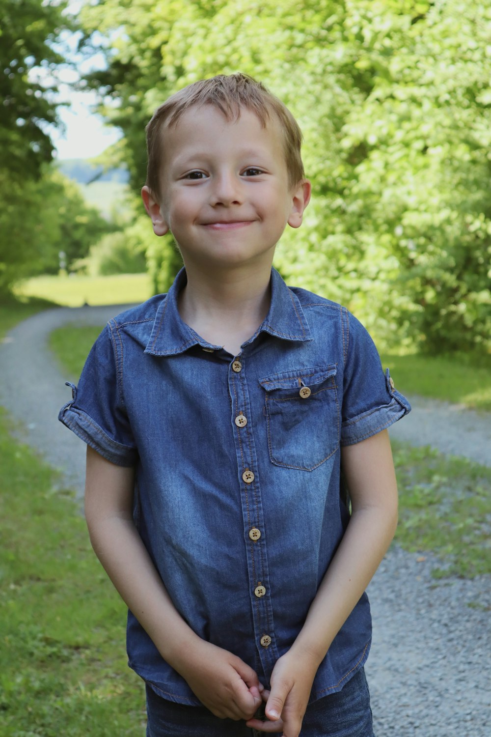 boy in blue button up shirt standing on green grass field during daytime