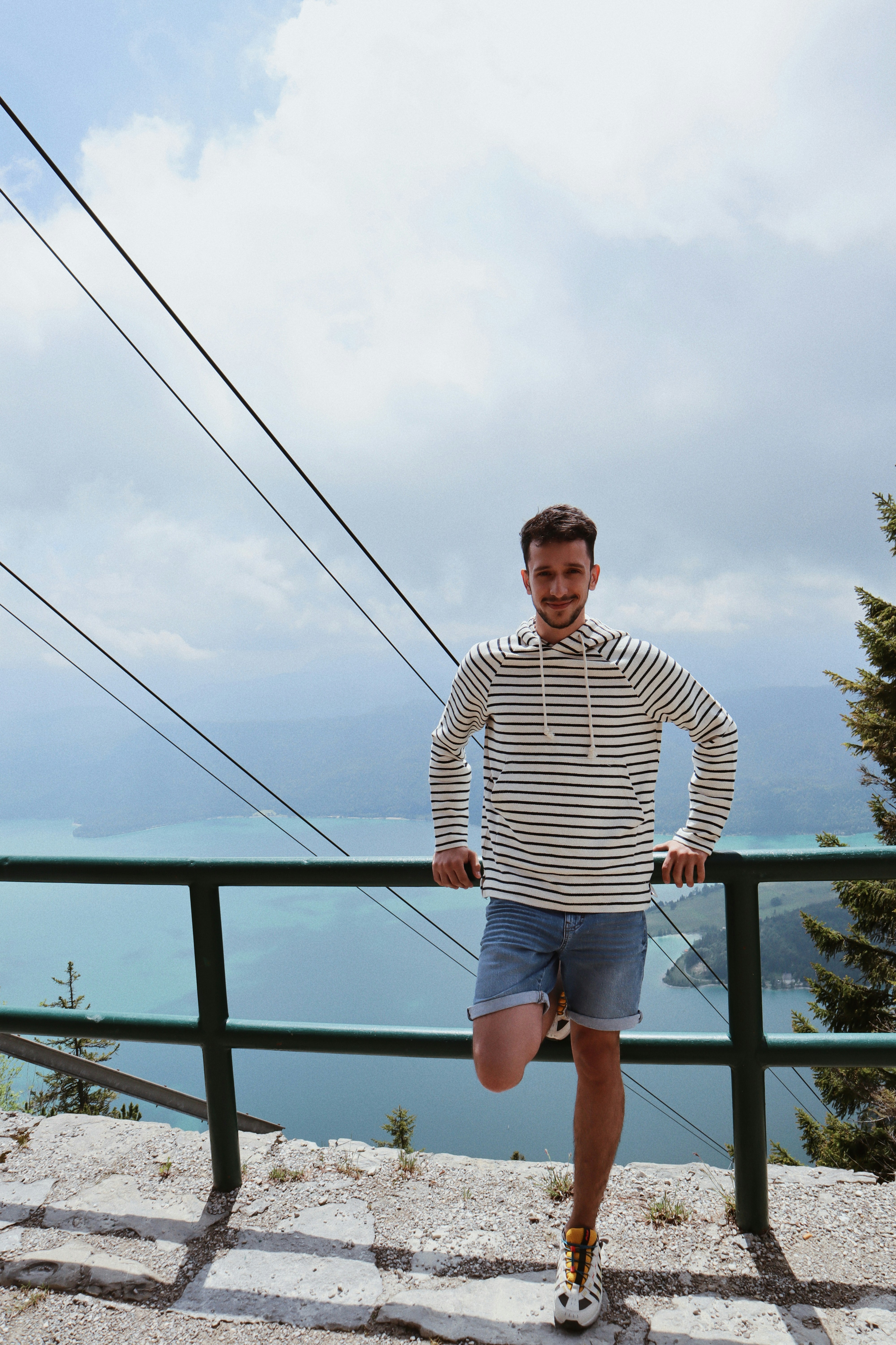 man in black and white striped long sleeve shirt standing on bridge during daytime