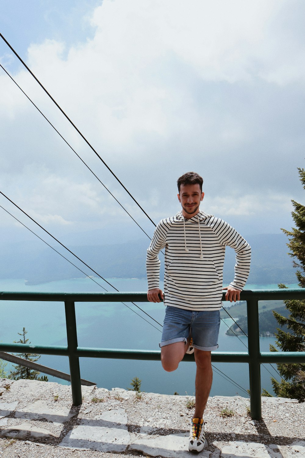 man in black and white striped long sleeve shirt standing on bridge during daytime