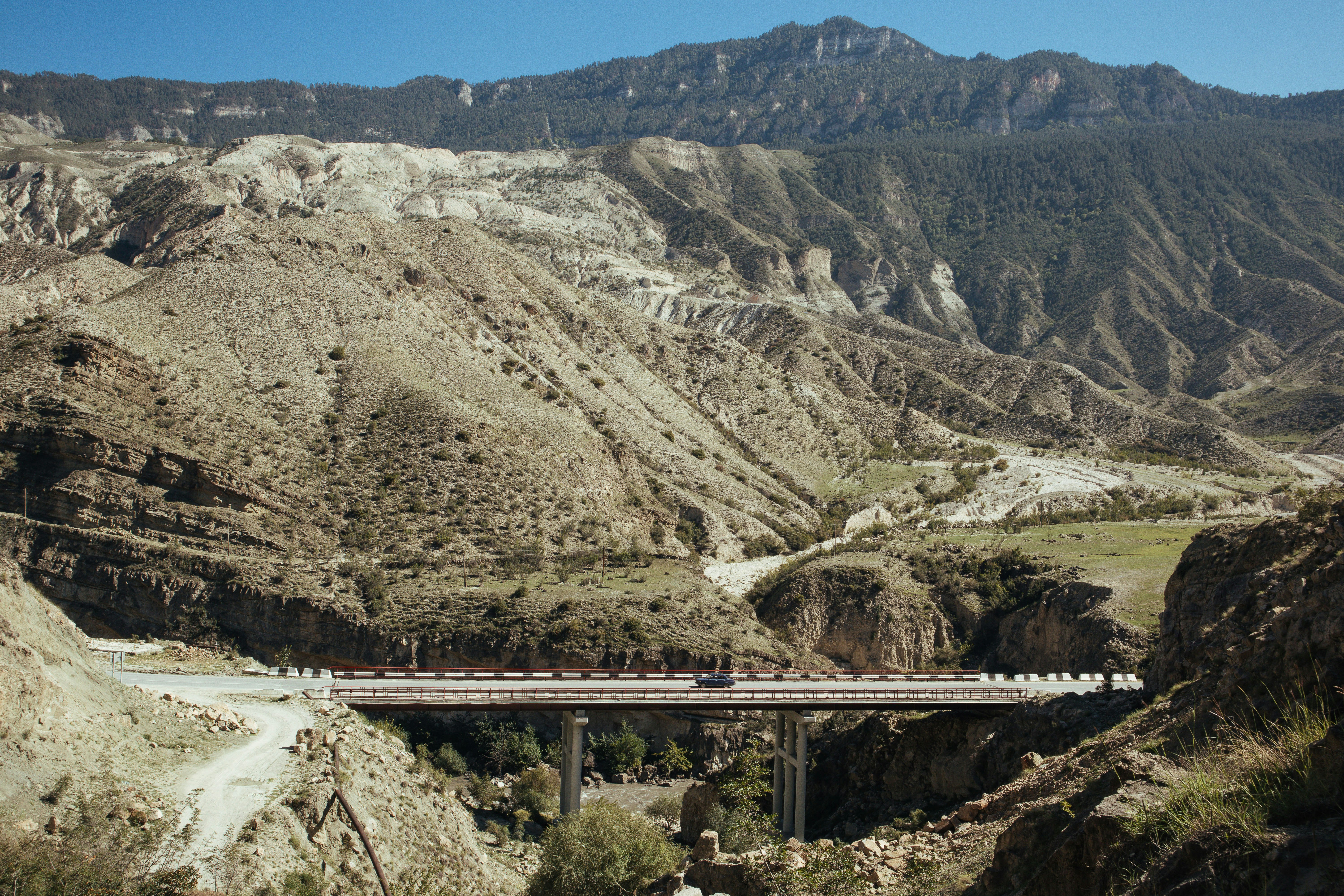 brown wooden bridge over river between mountains during daytime