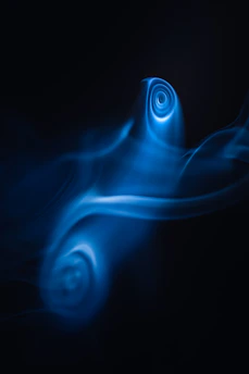 Swirls of neon blue light create ethereal patterns against a dark background, resembling smoke or liquid in motion. The forms suggest a sense of fluidity and mystery.