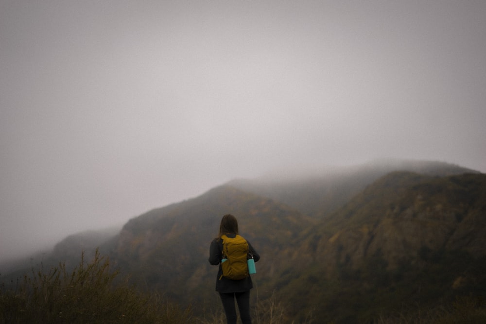 woman in black jacket and black pants standing on brown rock formation during daytime