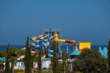 Water slide area featuring twisting blue and orange slides surrounded by lush greenery.