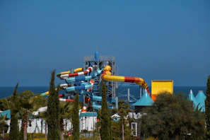 Water slide area featuring twisting blue and orange slides surrounded by lush greenery.
