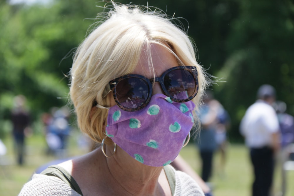woman in black sunglasses with purple and white face paint