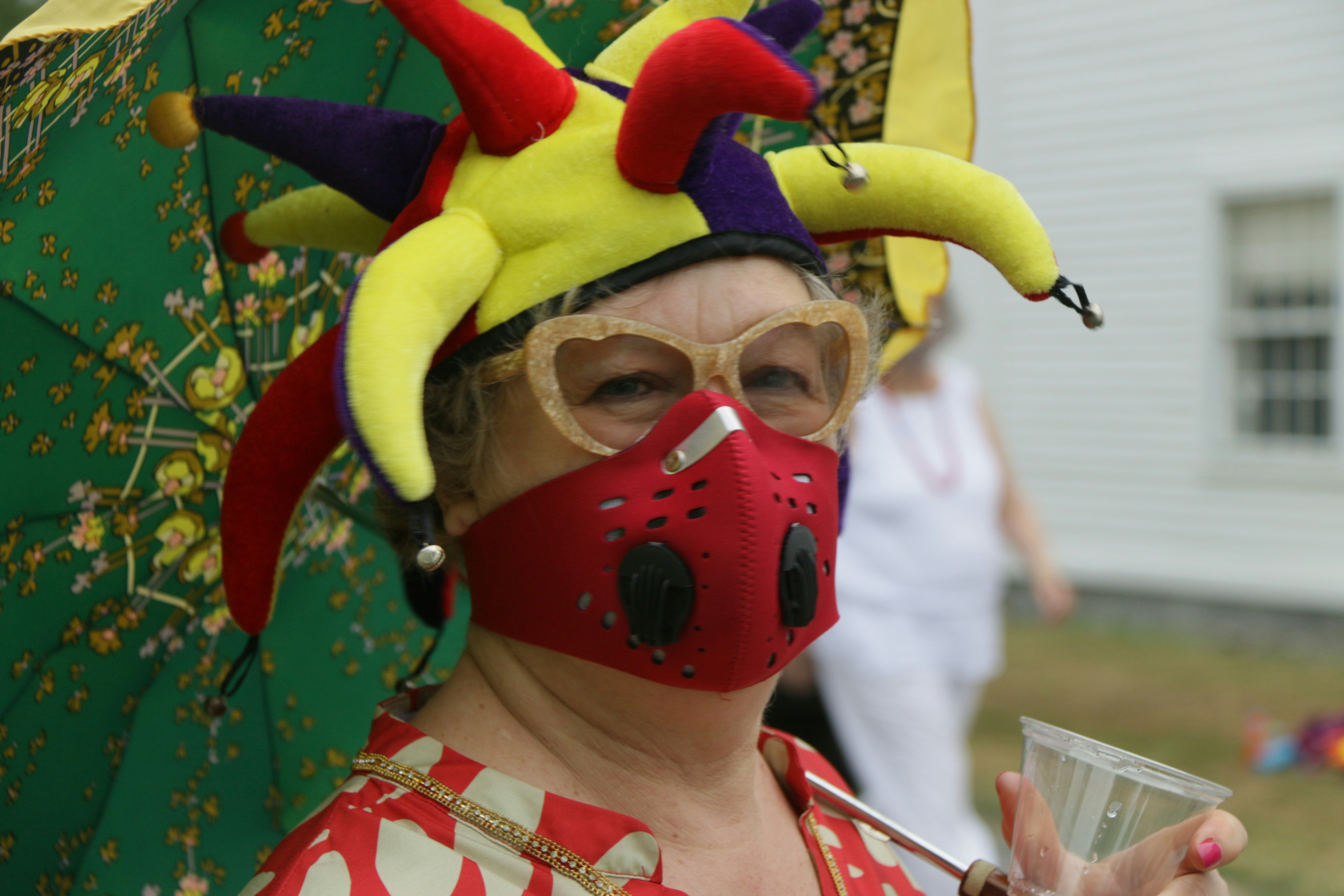 Covid Masks Socially Distanced Outdoors. Wearing colorful red mask and silly headwear.