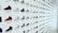 A wall featuring a vast array of Nike sneakers, presented in a grid format. Each sneaker is accompanied by a unique number code. The designs vary in color and style, ranging from high-top to low-top, and incorporating various color patterns and combinations.