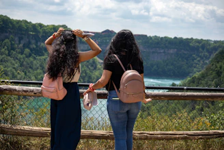 2 women standing on gray metal fence during daytime