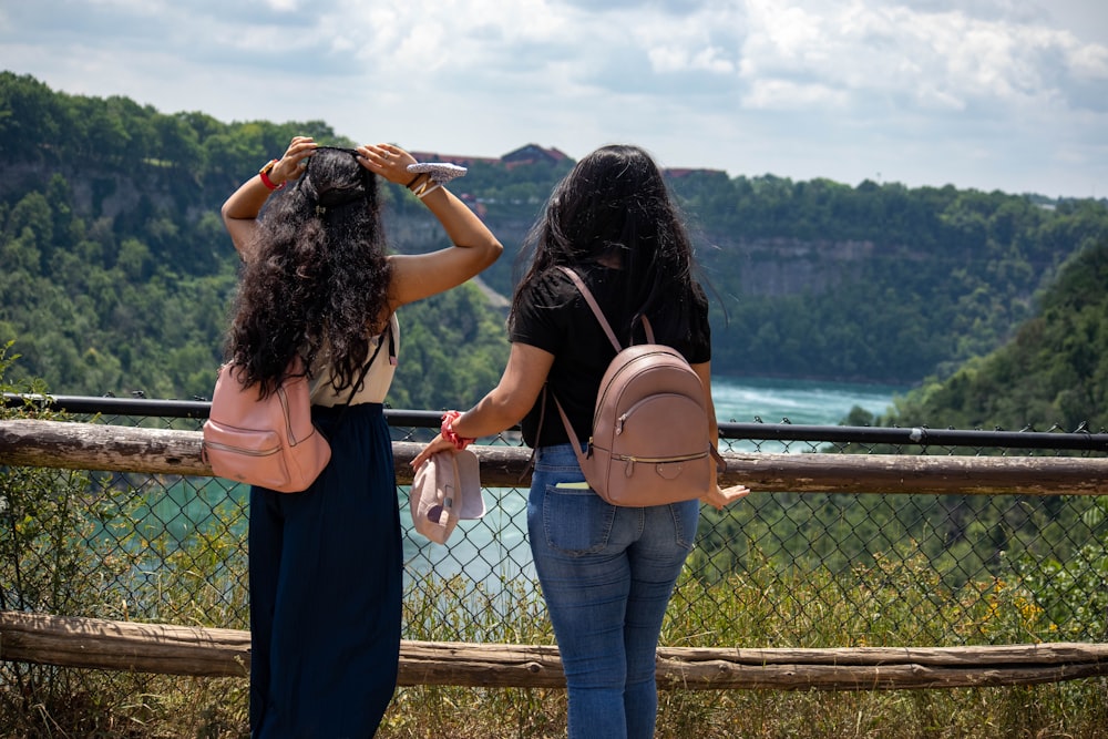 2 women standing on gray metal fence during daytime