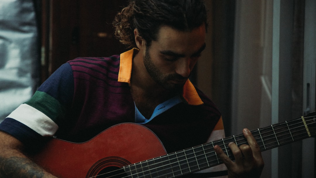 man in purple and black collared shirt playing guitar