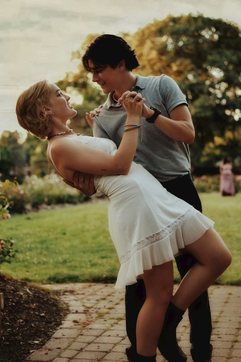 woman in gray shirt carrying girl in white dress